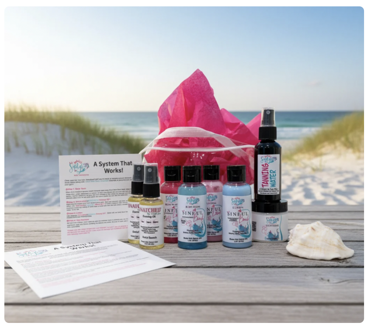 Beachside product display: pink tote and assorted spray bottles arranged on a wooden table with a seashell, ocean in the background.